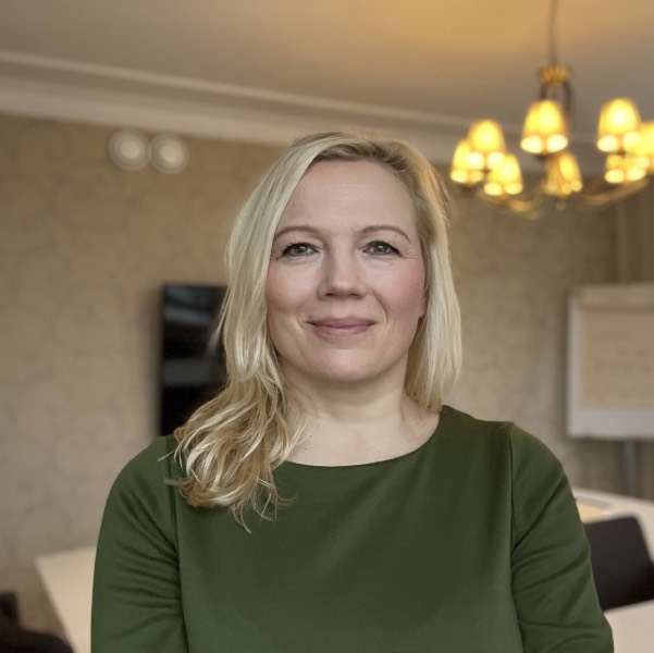 Nina hymyilee työhuoneessa.